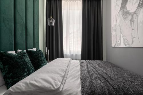 a bedroom with a bed with green curtains and a window at APARTIO ROOMS Katowice in Katowice