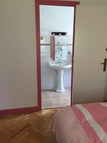 a bathroom with a sink and a mirror and a bed at Maison Art Deco-5 suites, piscine, clim, parking in Labouheyre