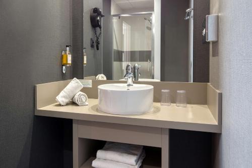 a bathroom with a sink and a large mirror at Best Western Hotel Atlantys Zenith Nantes in Saint-Herblain