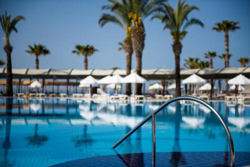 a swimming pool with palm trees and a resort at TUI BLUE Palm Garden in Kizilagac