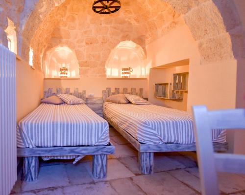 - 2 lits dans une chambre avec un mur en pierre dans l'établissement Trulli Colebè con Piscina, à Martina Franca