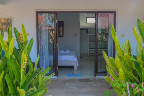 a room with a bed and sliding glass doors at Divine Divers Gili Meno in Gili Meno