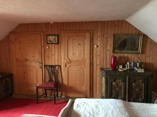 a bedroom with wooden walls and a bed and a chair at Sattelzimmer und Studio in Pischeldorf
