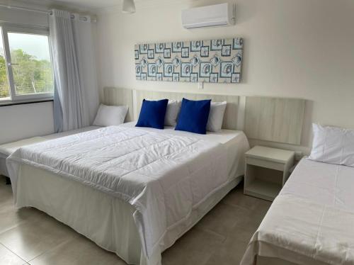 Un dormitorio con dos camas con almohadas azules. en Apartamento em Arraial D`Ajuda com Piscina Sauna Academia, en Porto Seguro