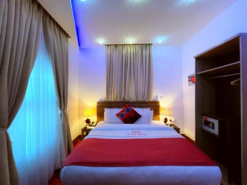 a bedroom with a large bed with a red blanket at Proof Hotel Lekki in Lagos