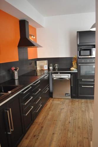 une cuisine avec des armoires noires et un plancher en bois dans l'établissement L Etoile De La Mer, à Berck-sur-Mer