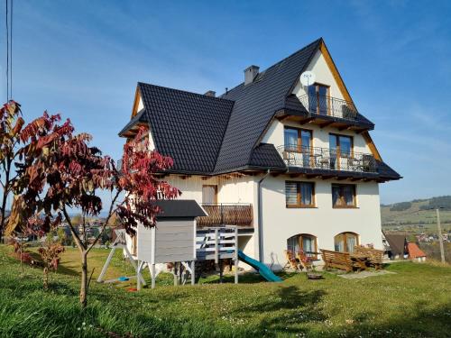 a large white house with a black roof at Pokoje u Hani - sauna, balia z hydromasażem in Bukowina Tatrzańska