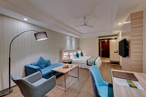 a hotel room with a bed and a couch and chairs at The Fern Residency Hubballi in Hubli