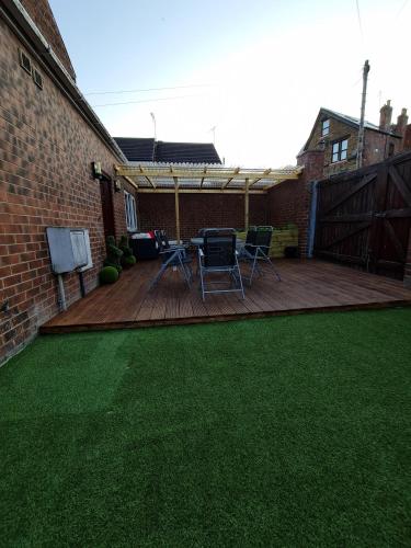 un patio trasero con una terraza con césped verde en Cooperage House All Ensuite Property - Sleeps 18 en Sheffield