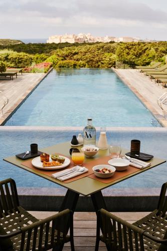a table with food on it next to a swimming pool at Hôtel & Spa Version Maquis Citadelle in Bonifacio