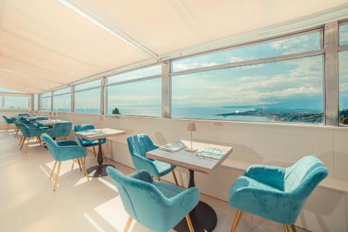 a restaurant with blue chairs and tables and windows at Hotel Villa Paradiso in Taormina
