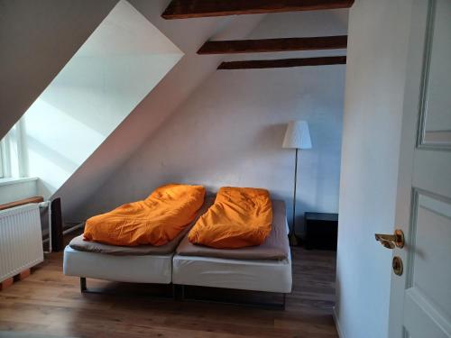 ein Zimmer mit einer Couch mit orangefarbener Bettwäsche darauf in der Unterkunft "City Sleep" in Nykøbing Mors