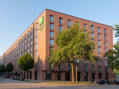 ein rotes Backsteingebäude mit einem Baum davor in der Unterkunft Holiday Inn - Hamburg - Berliner Tor, an IHG Hotel in Hamburg