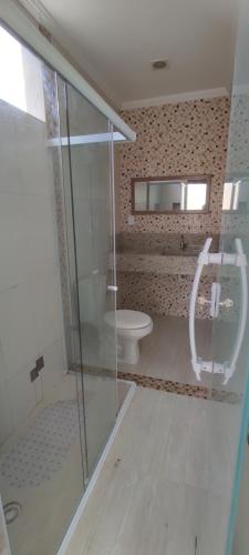 a bathroom with a glass shower and a toilet at Casa Praia Dunas do Peró in Cabo Frio