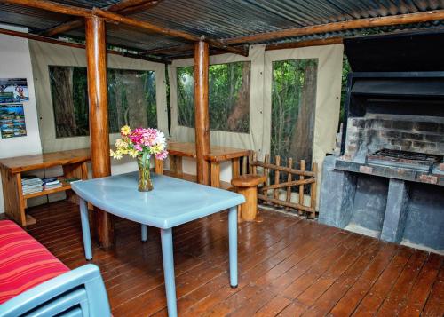 a vase of flowers on a table on a porch with a fireplace at Stanford Lake lodge in Haenertsburg