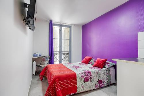 - une chambre avec des murs violets et un lit avec des oreillers rouges dans l'établissement Hotel Monte-Cristo, à Marseille