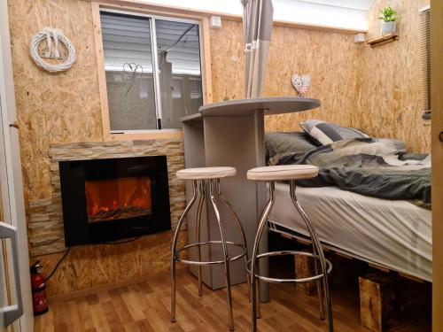 een slaapkamer met een bed en 2 krukken voor een open haard bij La roulotte in Travers