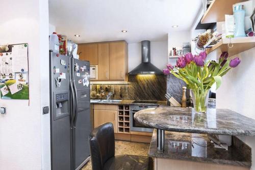 een keuken met een koelkast en een tafel met paarse bloemen bij Bezaubernder Bungalow im Fünfseenland nähe S-Bahn in Gauting