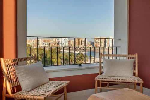 two chairs on a balcony with a view of a city at Only YOU Hotel Málaga in Málaga