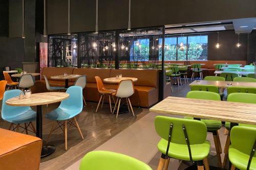 a restaurant with wooden tables and green chairs at XO Hotels Couture in Amsterdam