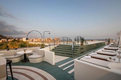 a beach area with chairs, tables, and a balcony at Only YOU Hotel Málaga in Málaga