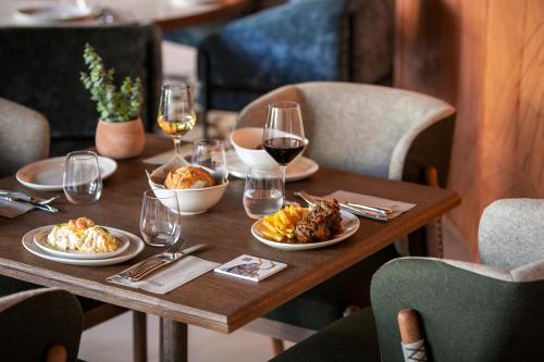a wooden table with plates of food and glasses of wine at Only YOU Hotel Málaga in Málaga