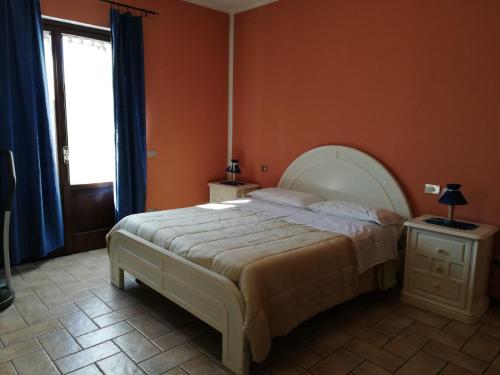 een slaapkamer met een groot bed met een oranje muur bij Locanda della Braccesca in Ponte Pattoli