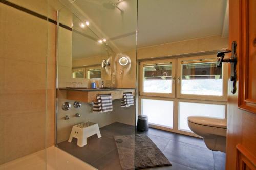 a bathroom with a toilet and a glass shower at Bojernhof in Ruhpolding