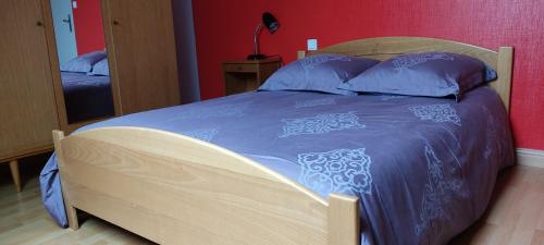 1 dormitorio con cama de madera y manta azul en Chambres au Village, en Saint-Mʼhervé