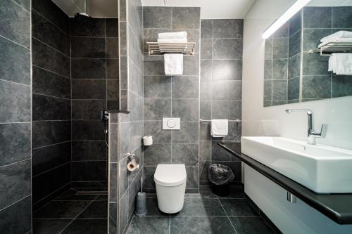 a bathroom with a toilet, sink, and bathtub at Bastion Hotel Nijmegen in Nijmegen