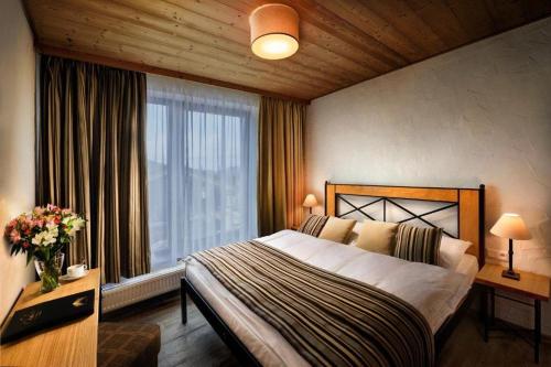 ein Schlafzimmer mit einem großen Bett und einem großen Fenster in der Unterkunft Chalet Jasná Wellness Apartment Saskia jacuzzi & sauna in Demänovská Dolina