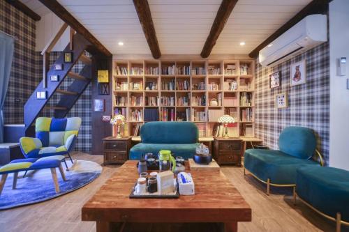 a room with blue chairs and a table and bookshelves at 白鹿詩行旅 in Tainan