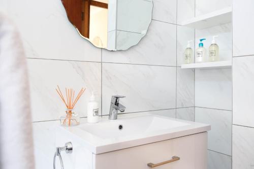 a white bathroom with a sink and a mirror at 5 bedroom Traditional Fisherman's old Gem w panoramic views, Bloubergstrand, Cape Town in Bloubergstrand