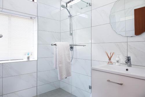 a white bathroom with a shower and a sink at 5 bedroom Traditional Fisherman's old Gem w panoramic views, Bloubergstrand, Cape Town in Bloubergstrand