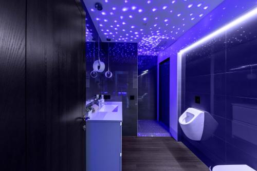 a bathroom with purple lighting and a sink and a urinal at sky FLAT jacuzzi sauna 27 FLOOR in Klaipėda