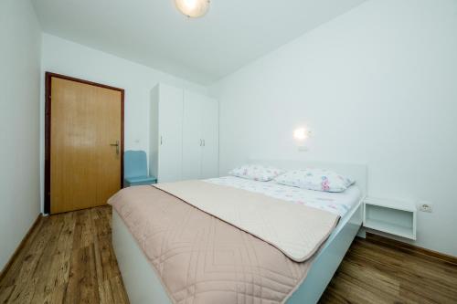 a white bedroom with a bed with two pillows on it at Željko Apartmani in Lopar