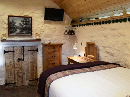 a bedroom with a bed and a tv on the wall at Capercaillie Cottage in Rhilochan