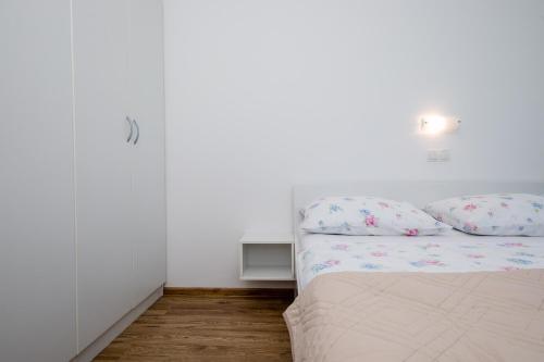 a white bedroom with a bed with pillows at Željko Apartmani in Lopar