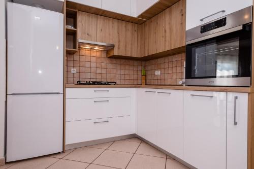 a kitchen with white cabinets and a microwave at Željko Apartmani in Lopar