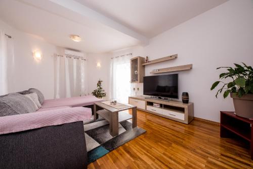 a living room with a couch and a flat screen tv at Željko Apartmani in Lopar