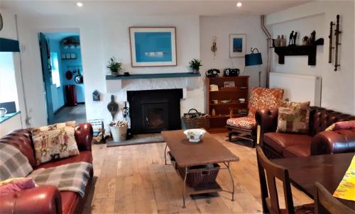 ein Wohnzimmer mit Ledermöbeln und einem Kamin in der Unterkunft The Rockhouse - Cosy stone built Thatch Cottage in Dungloe