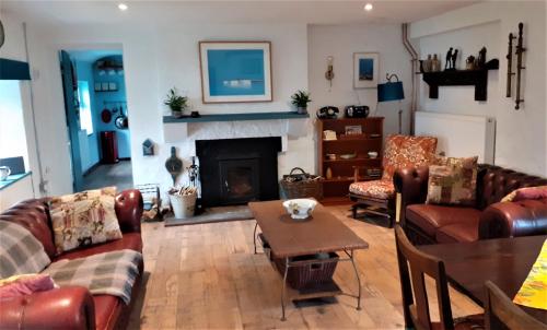 a living room with leather furniture and a fireplace at The Rockhouse - Cosy stone built Thatch Cottage in Dungloe