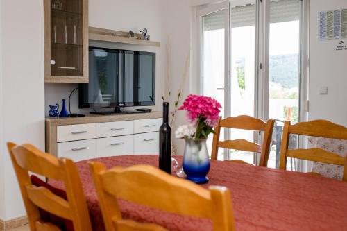a dining room table with a vase of flowers on it at Željko Apartmani in Lopar
