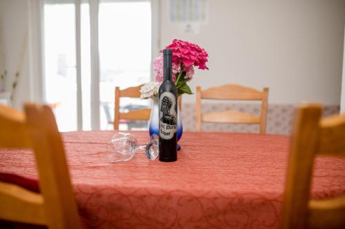 a bottle of wine sitting on a table with flowers at Željko Apartmani in Lopar