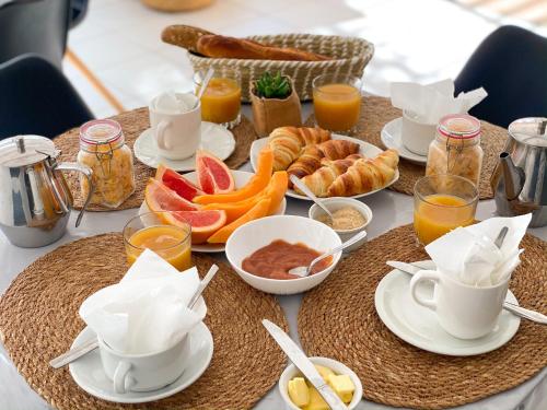 a table with a breakfast of croissants and orange juice at Hotel Oasis in Grande Anse