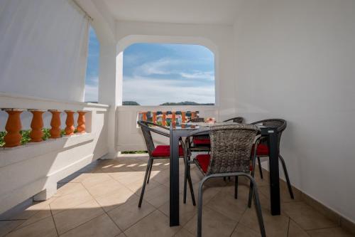 a table and chairs in a room with a window at Željko Apartmani in Lopar