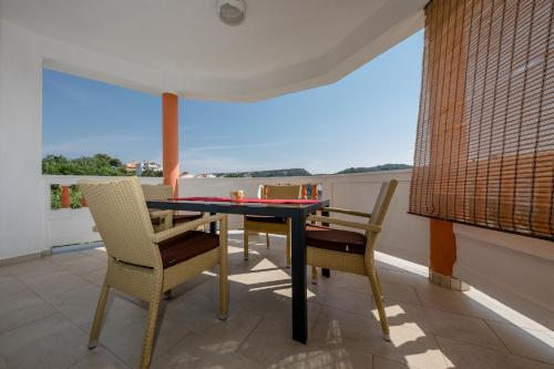 a dining room with a table and chairs on a balcony at Željko Apartmani in Lopar