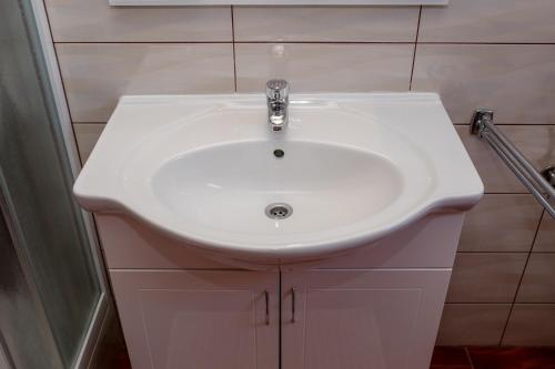 a white sink in a bathroom with white cabinets at Željko Apartmani in Lopar
