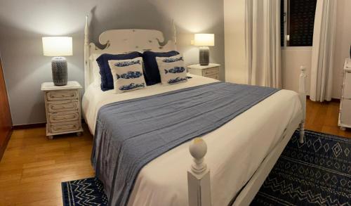 a bedroom with a large bed with blue pillows at Madalena Sunset by Madeira Sun Travel in Madalena do Mar