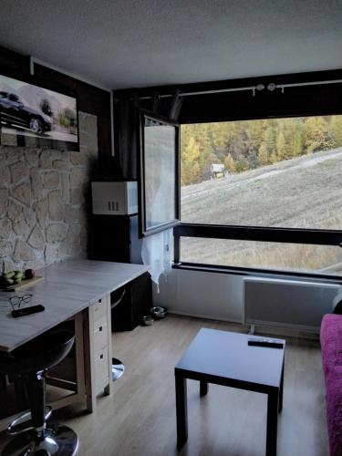 a room with a desk and a large window at STUDIO 20m2 in Puy-Saint-Vincent